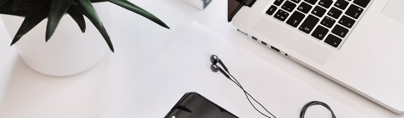 Work Desk with white laptop and black ear buds